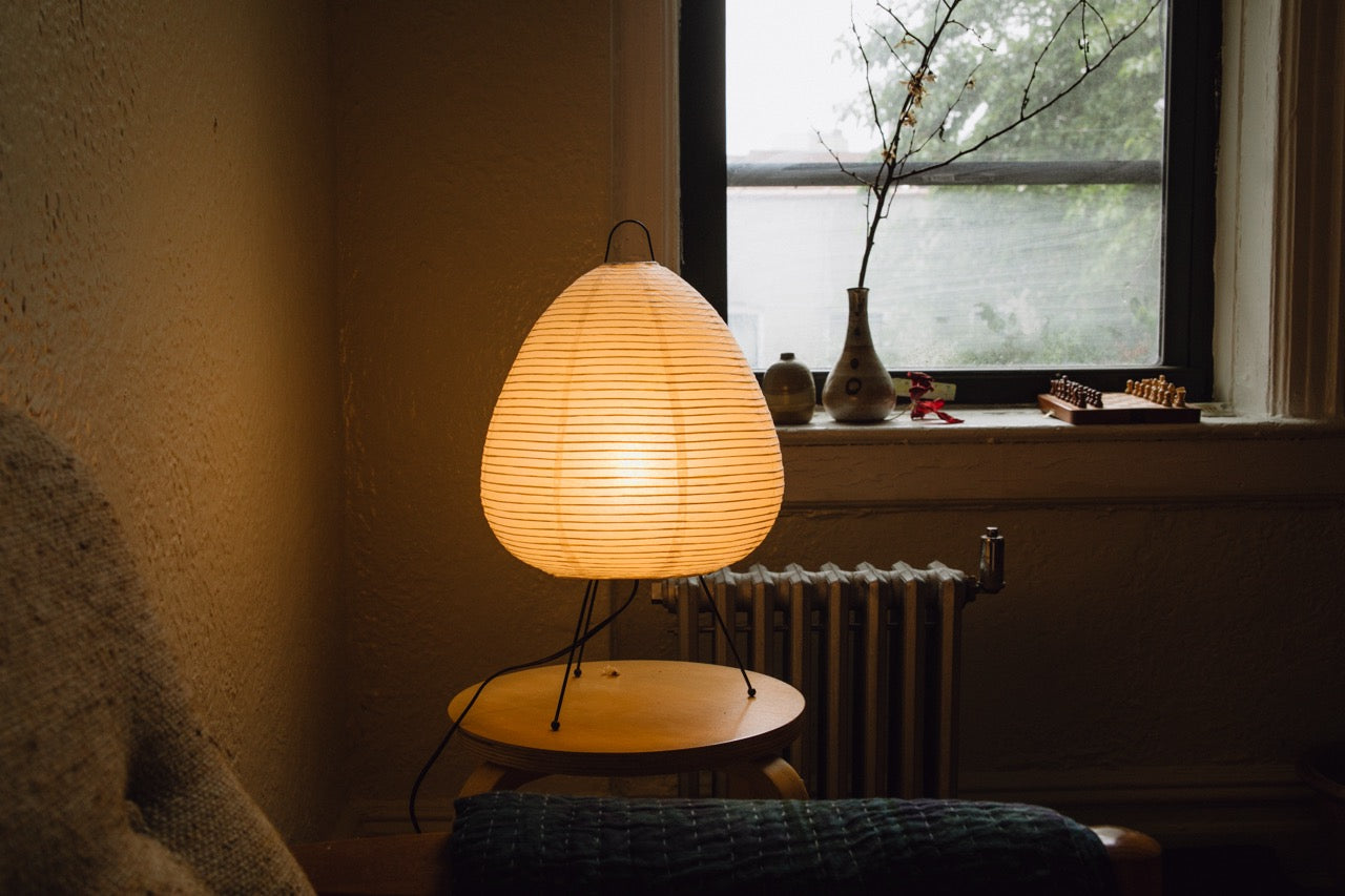 The Akari Suiteki - Lucy’s Lamps is a minimalist paper lantern table lamp inspired by Japanese design. This aesthetic and modern table lamp adds a warm glow to bedrooms, living rooms, or workspaces. Perfect as a bedside lamp, side table lamp, or desk lamp, it blends retro charm and modern designer lighting for elegant, timeless home décor.